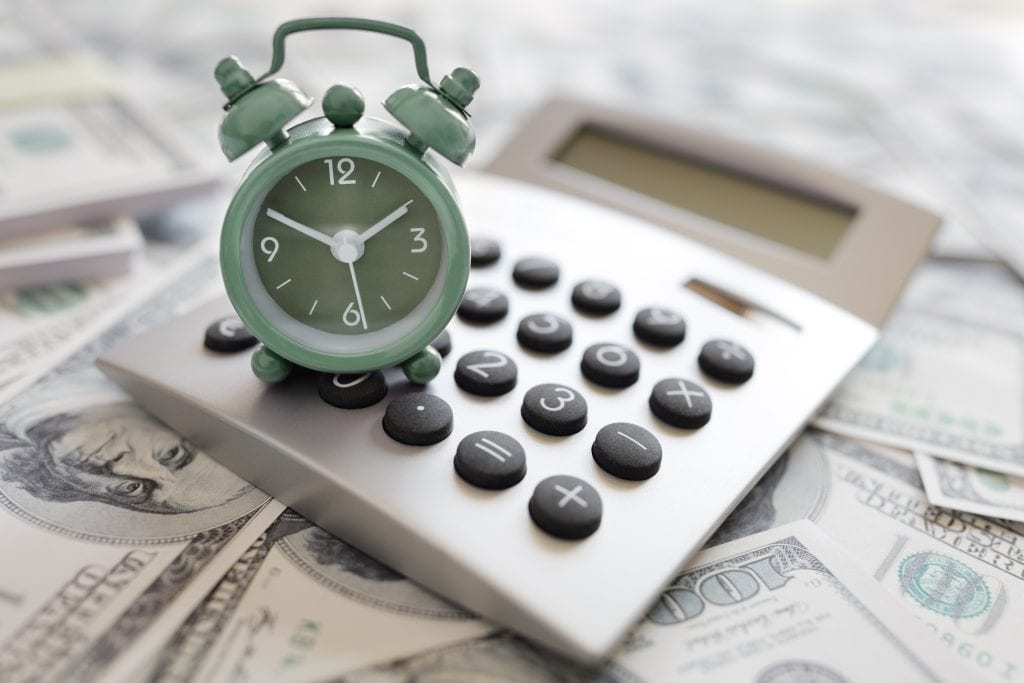 real estate investment group; a green clock is on top of a calculator