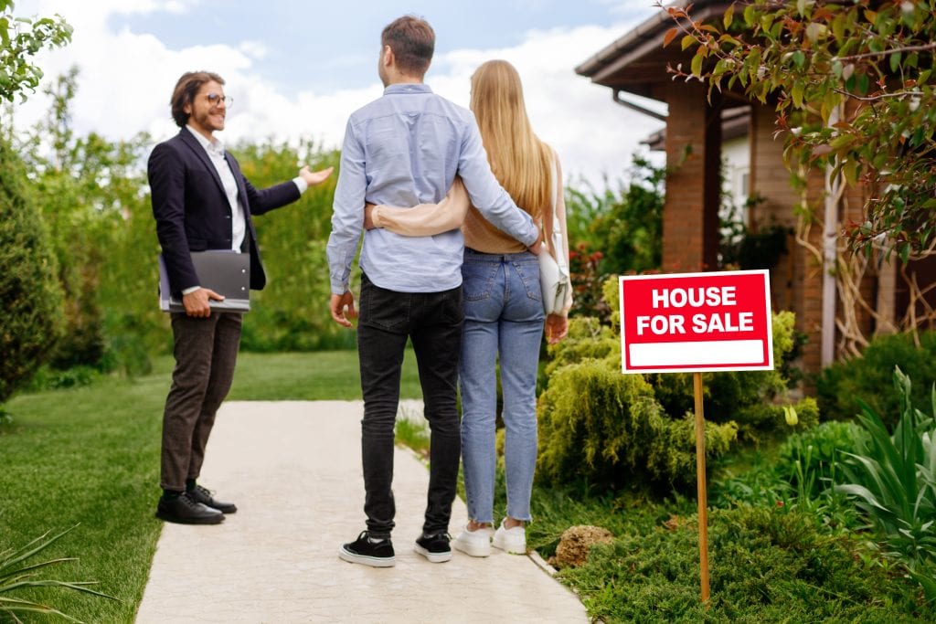 a real estate agent is showing a young couple a house for sale